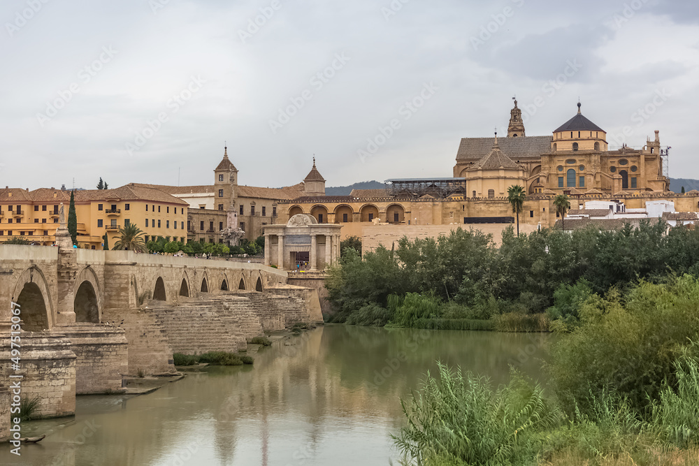 View at the Roman Bridge over Guadalquivir river, Mosque-Cathedral of Córdoba, Roman Catholic Diocese and Plaza del Triunfo as background, Cordoba downtown, Spain