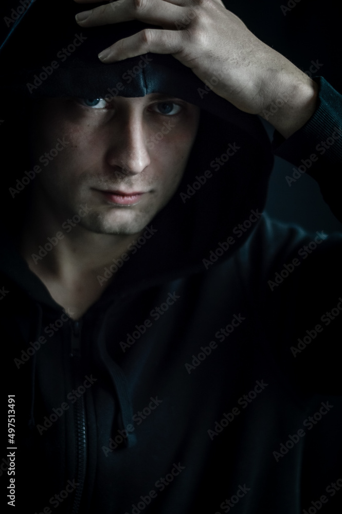 Portrait of a young man adjusting the hood on his head with his hand