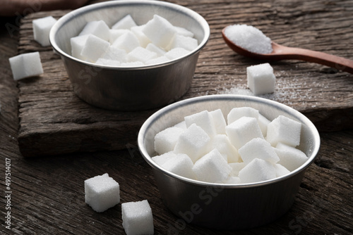 White Sugar cubes in aluminium bowl on wooden plate