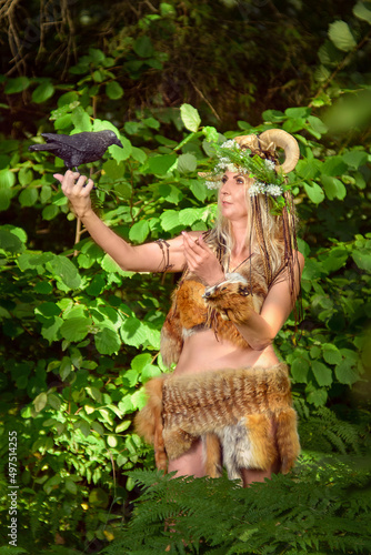 Woman in the forest dressed in skins and fur. On the head of the crown from the horns. Fabulous concept.