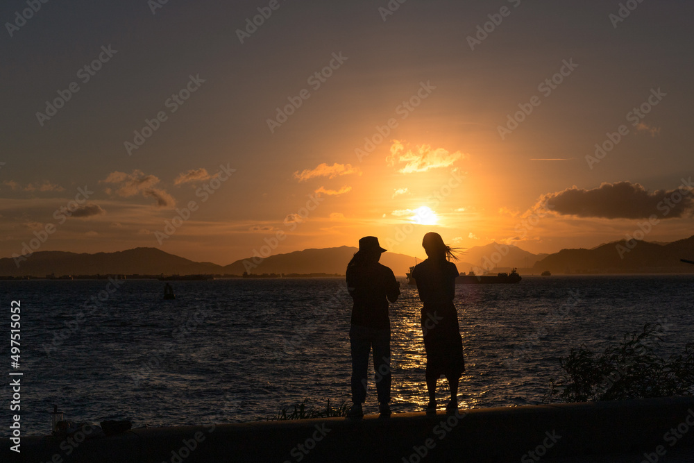 two stylish girl or lady chat at seaside during sunset in evening. Back light view