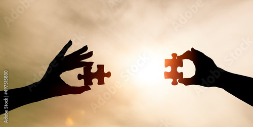 Zwei Hände fügen zwei Puzzleteile zusammen
