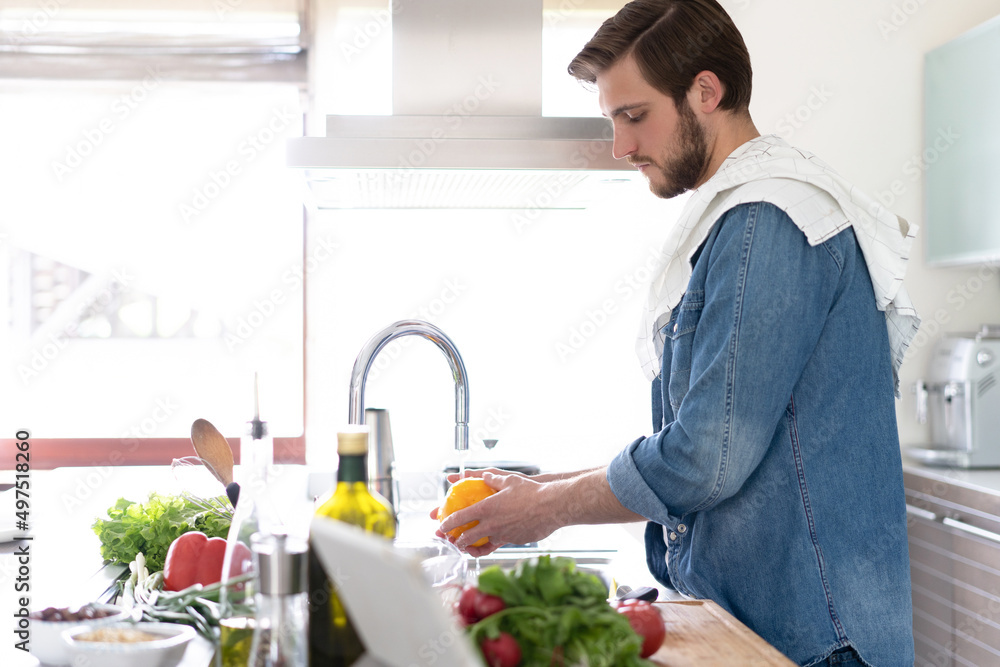 Portrait of man preparing wash fresh vegetables salad splashing in water on counter standing in the home kitchen. Portrait of man preparing wash fresh vegetables salad splashing in water on counter standing in the home kitchen.