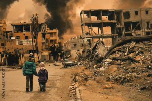 Two homeless little girl walking in destroyed city, soldiers and helicopters and tanks are still attacking the city photo