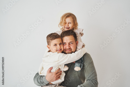 Happy family. Father, daughter and son hugging and smiling on white background. Paternity. Single father bring up his children.