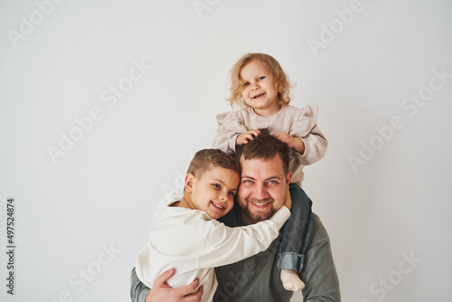 Close-up portrait of father, son and daughter. Happy family hugging and smiling on white background. Paternity. Single father bring up his children.