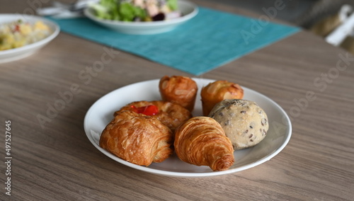 Homemade mini apple pie, croissant, spinach pie, organic whole wheat bread Almond Muffins Place in a plate on a wooden table for serving with hot drinks. with blur background of vegetable salad plate 