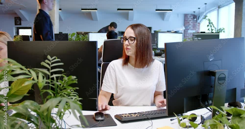 Busy Caucasian woman sitting at computer screen and typing on keyboard. Customer support online. Female employee working at office and texting. IT worker. Workday at coworking center.