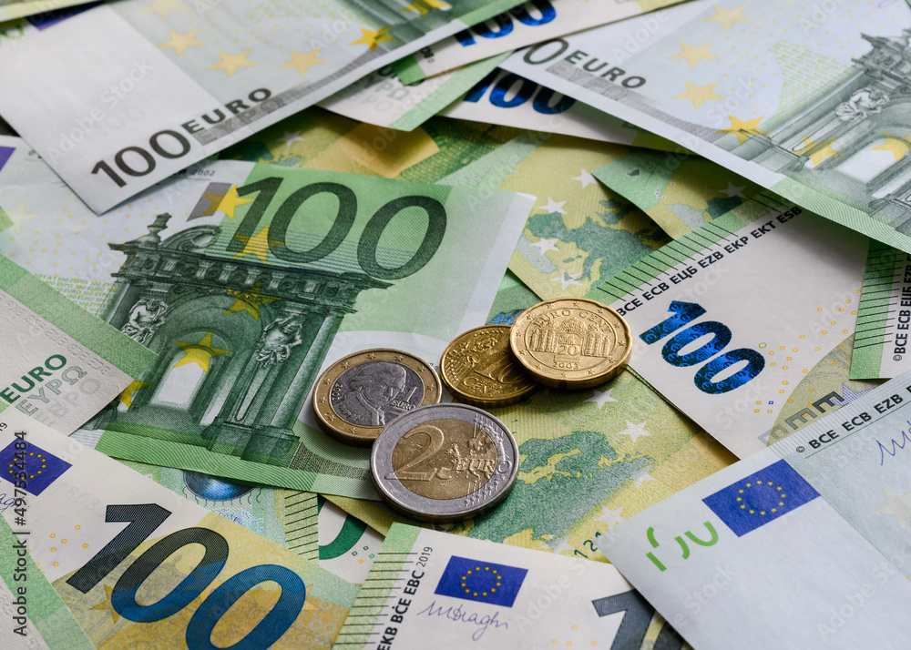 Euro cent coins on the background of 100 Euro banknotes arranged in random order Euro cent coins on the background of 100 Euro banknotes arranged in random order