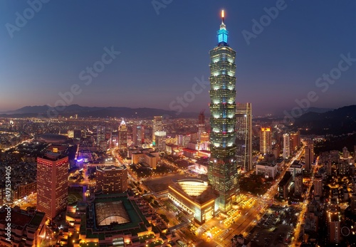 Aerial skyline of Downtown Taipei at dusk, vibrant capital city of Taiwan, with 101 Tower standing out amid skyscrapers in Xinyi Commercial District and oval shaped Taipei Dome located in nearby area