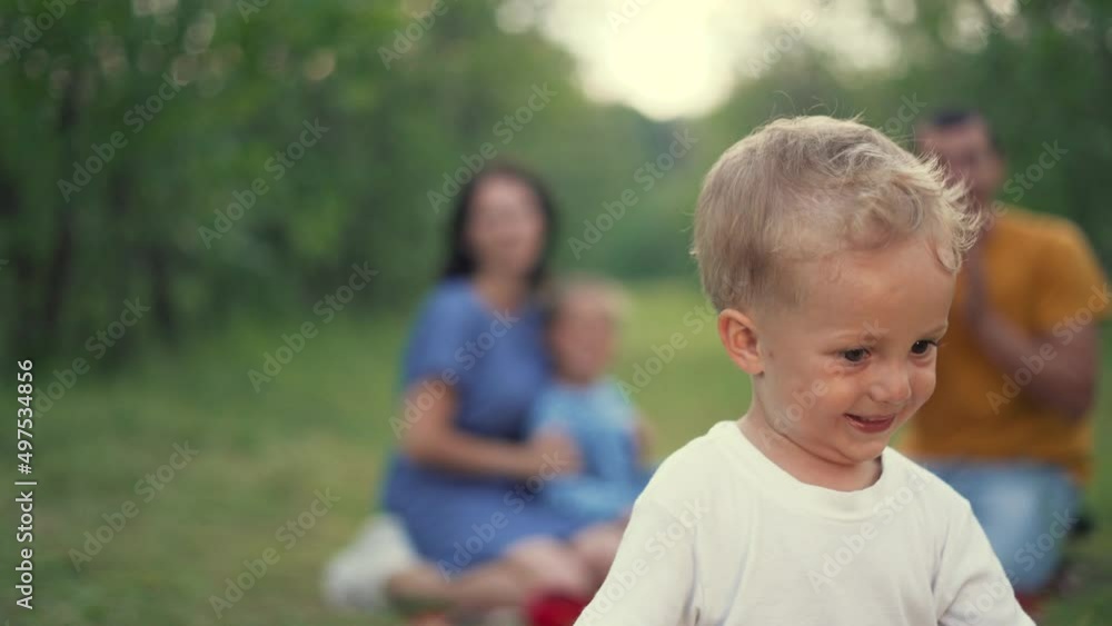 Happy family in the park. Parents teach the child. Picnic on the green grass. The first steps of the baby on the green grass. Family picnic in the park. games in the forest meadow. Happy kid dream Happy family in the park. Parents teach the child. Picnic on the green grass. The first steps of the baby on the green grass. Family picnic in the park. games in the forest meadow. Happy kid dream