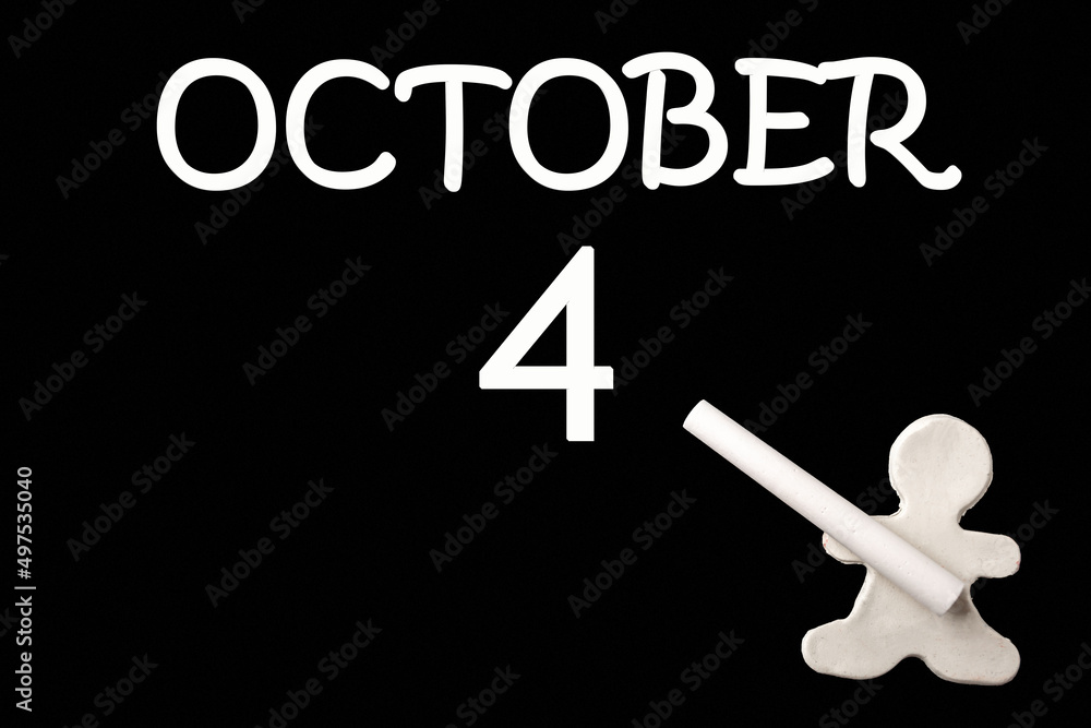 A small white plasticine man writing the date 4 October on a black board. Business concept. Education concept. A small white plasticine man writing the date 4 October on a black board. Business concept. Education concept.