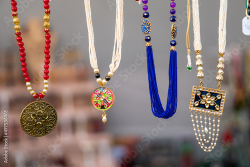 Close-up shot of some jewelry necklaces hanging in the air in a blurry background. photo