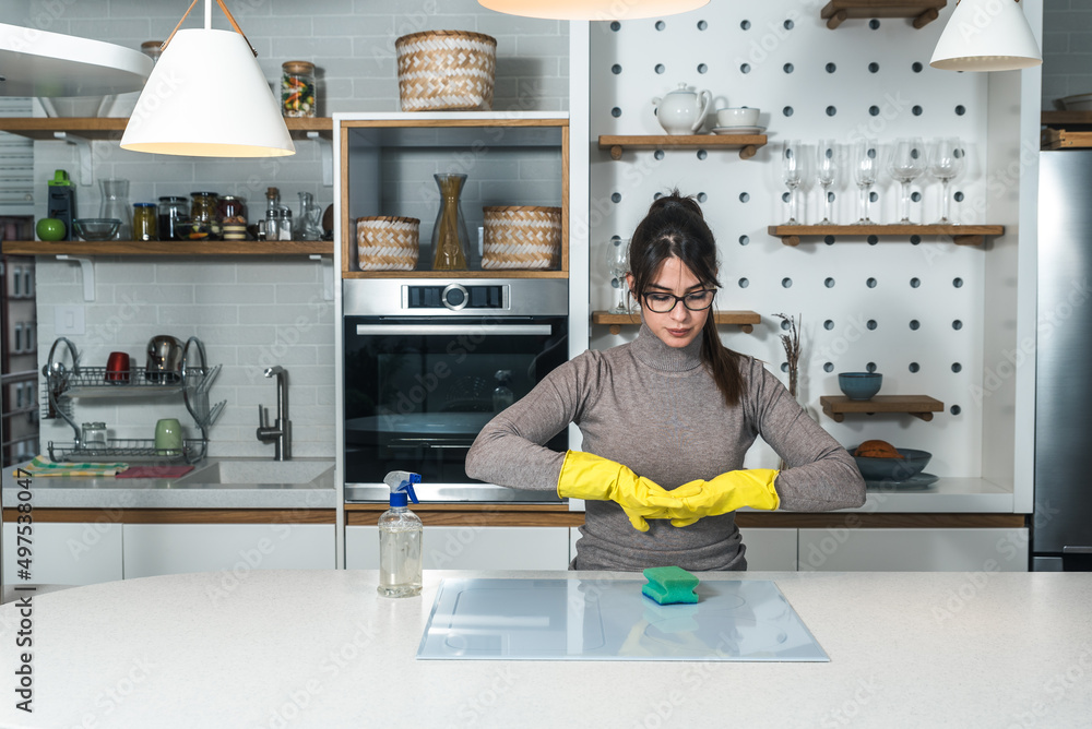 Young woman suffers from depression after a breakup or divorce and from obsessive compulsive disorder OCD cleans kitchen cook top to calm her nerves. Serious stressed female rubbing the home Young woman suffers from depression after a breakup or divorce and from obsessive compulsive disorder OCD cleans kitchen cook top to calm her nerves. Serious stressed female rubbing the home