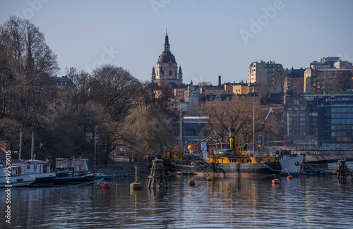 Panorama view with a passage with a bridge at the island Skeppsholmen, pier with boats and the old town Gamla Stan a sunny spring day in Stockholm