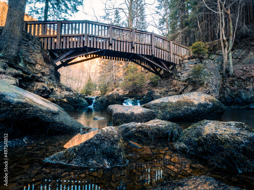 Beautiful shot of a wooden old bridge over a river with boulders in Verlobungsinsel island, Germany photo