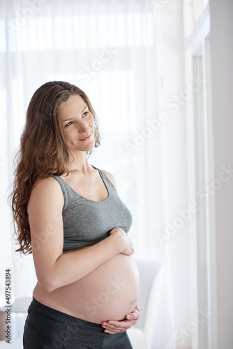 Glowing and healthy. Cropped shot of a young pregnant woman standing in her home.