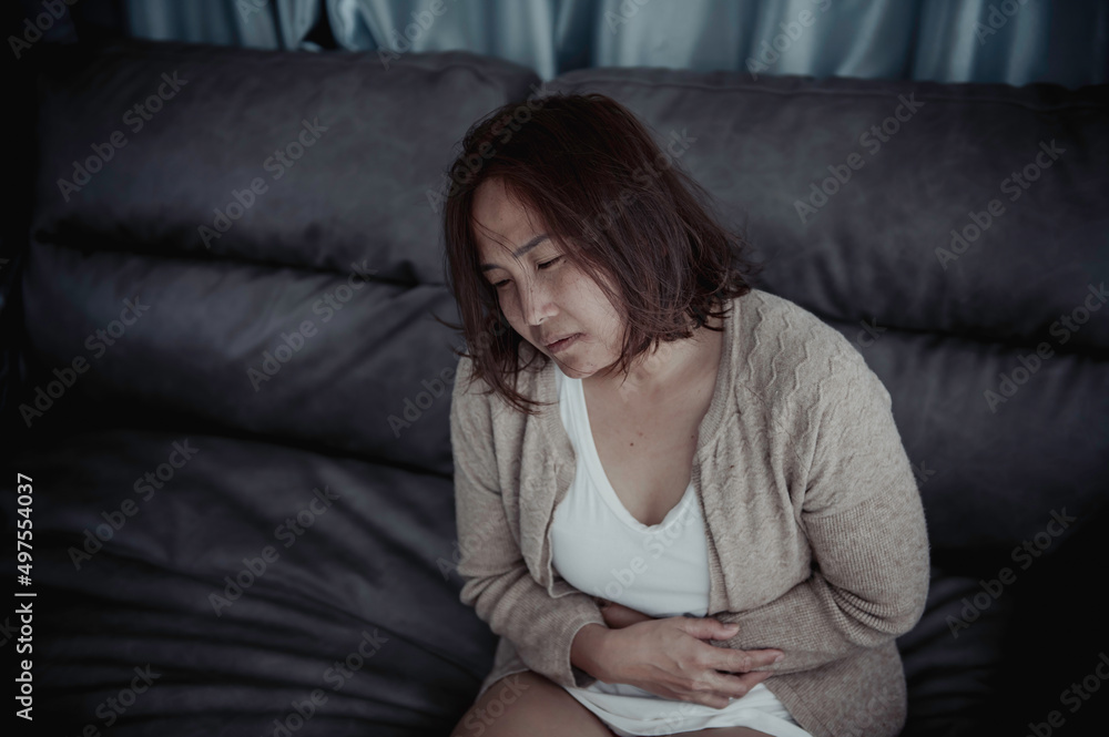 Asian sick woman sit on the sofa stay at home,The woman felt bad, wanted to lie down and rest,stomach ache,menstrual pain Asian sick woman sit on the sofa stay at home,The woman felt bad, wanted to lie down and rest,stomach ache,menstrual pain