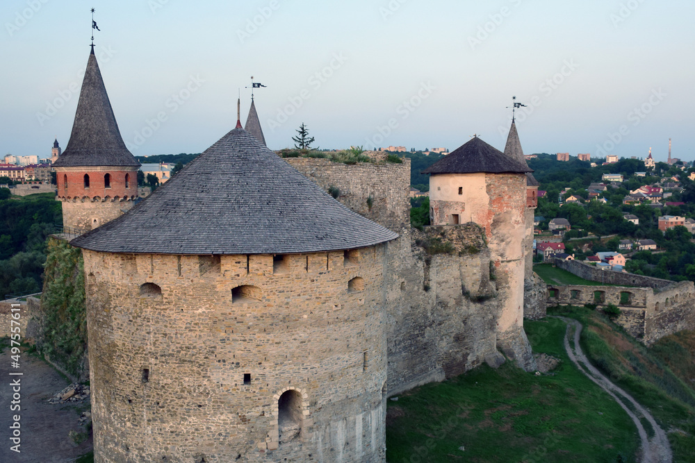 A large stone fortress with several towers in the background of the city. High angle view
