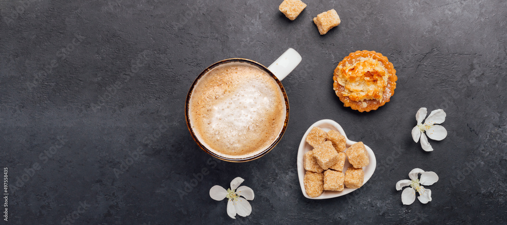 Cup of coffee with cakes and spring flowers on dark stone background. Horizontal banner. Top view Cup of coffee with cakes and spring flowers on dark stone background. Horizontal banner. Top view
