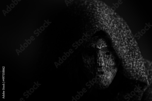 Portrait of a deamon in a dark mask on a black background with copy space photo