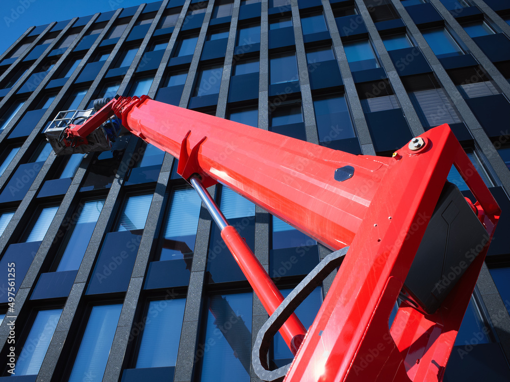 Cleaner workers using a cherry picker to clean a facade of a contemporary office building.