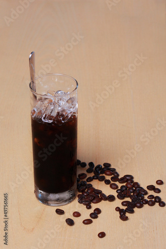 Glass of iced coffee and beans isolated on wooden table