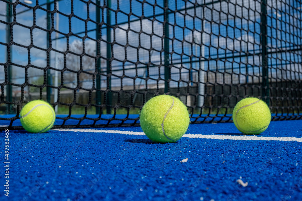 three balls near the net in a blue paddle tennis court