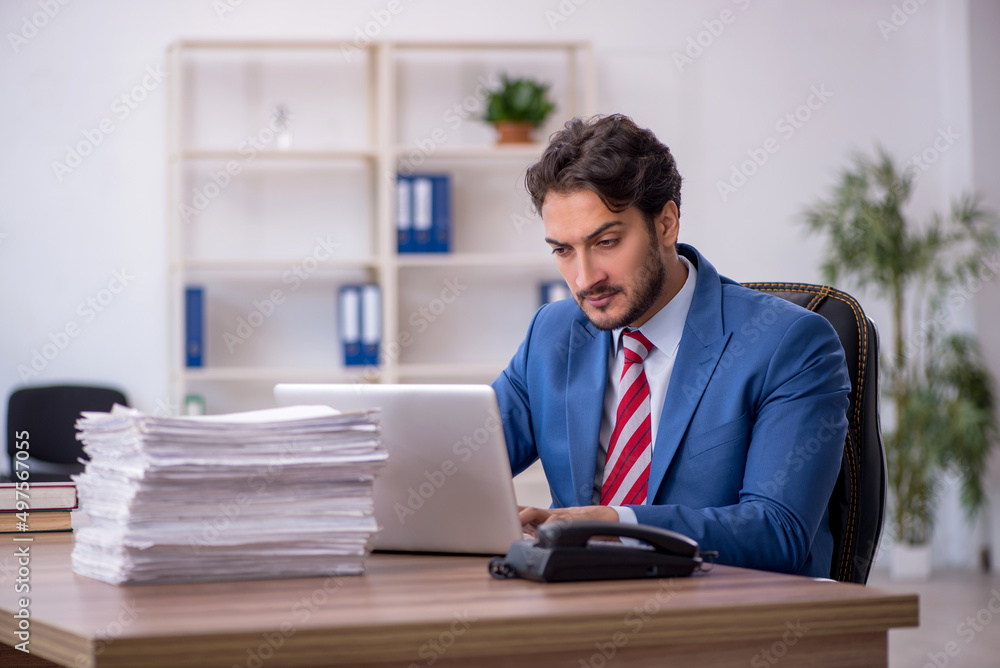 Young male employee and too much work in the office Young male employee and too much work in the office