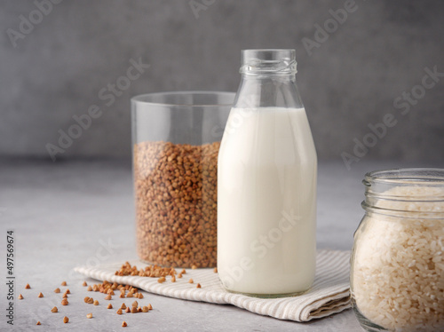 Non dairy alternative milk. Vegan buckwheat and rice milk close up. The concept of healthy vegetarian food and drinks. Copy space. A bottle of raw milk on a gray table and napkin. Diet healthy concept