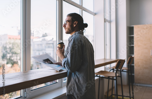 Photos Contemplative male spending time in coffee shop analyzing news from printed mass