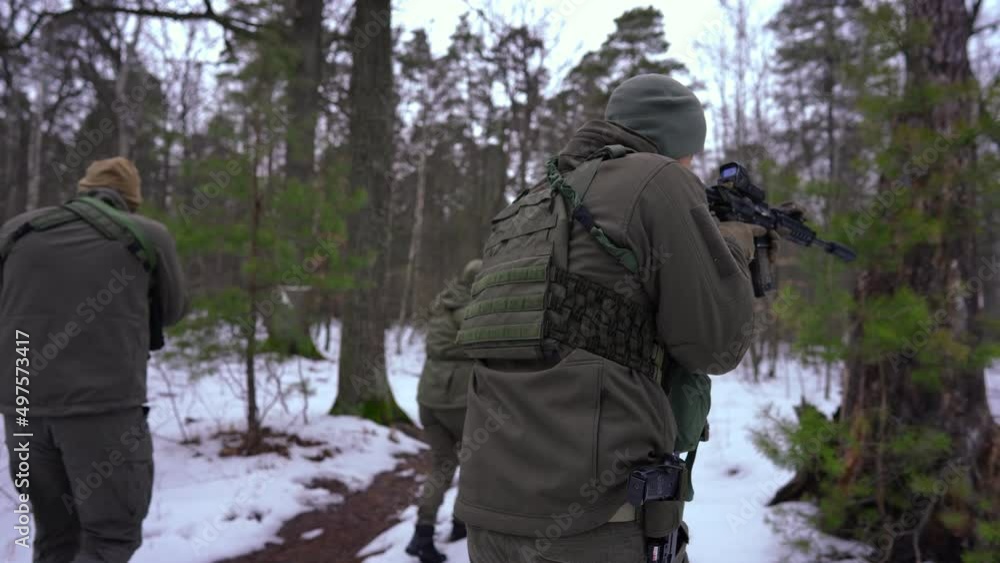 Live camera follows armed cautious people walking in winter forest aiming looking around. Young Ukrainian men and women fighting for independence searching enemy outdoors. War concept and defense Live camera follows armed cautious people walking in winter forest aiming looking around. Young Ukrainian men and women fighting for independence searching enemy outdoors. War concept and defense