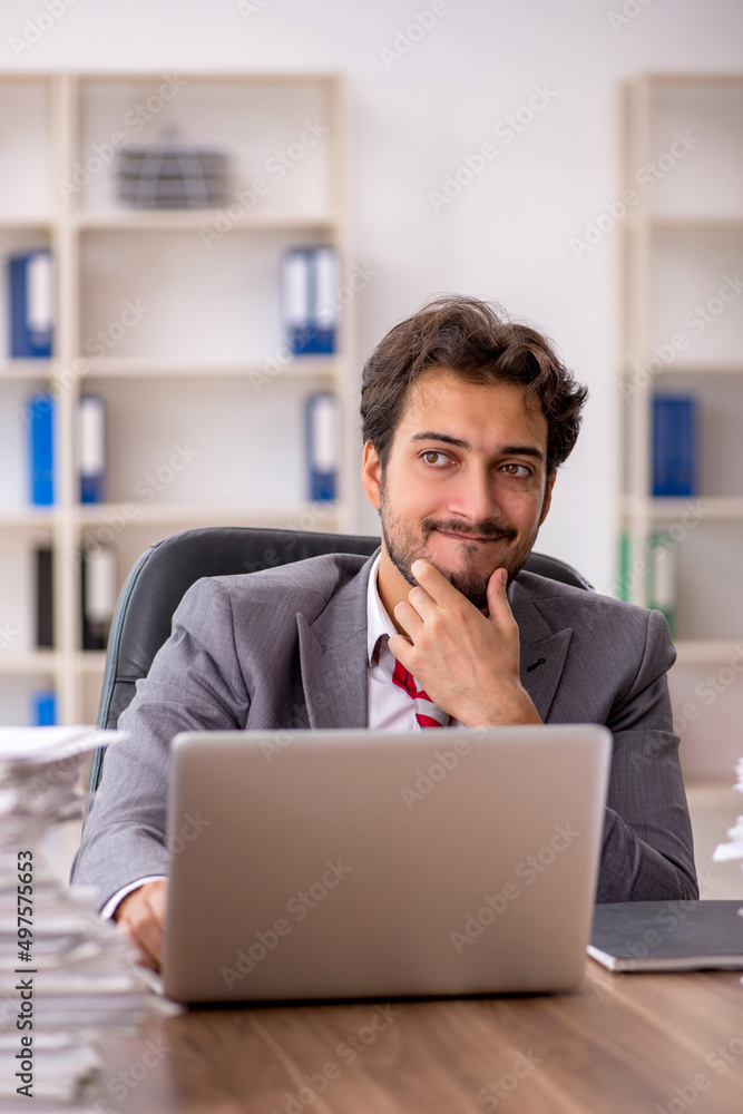 Young male employee unhappy with excessive work in the office Young male employee unhappy with excessive work in the office