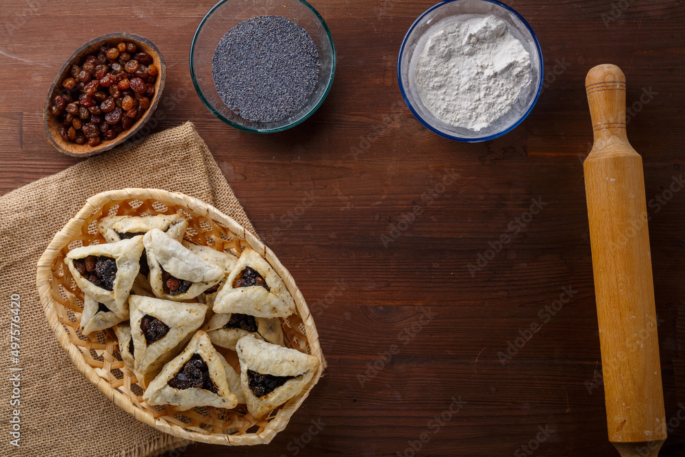 Gomentash with poppy seeds and prunes freshly baked for the Purim holiday on a wooden table on a linen napkin Gomentash with poppy seeds and prunes freshly baked for the Purim holiday on a wooden table on a linen napkin