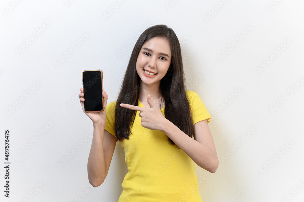 Portrait photo of young beautiful Asian woman pointing at black empty space on smart phone background can use for advertising or product presenting concept. Asian woman pointing at empty smart phone . Portrait photo of young beautiful Asian woman pointing at black empty space on smart phone background can use for advertising or product presenting concept. Asian woman pointing at empty smart phone .