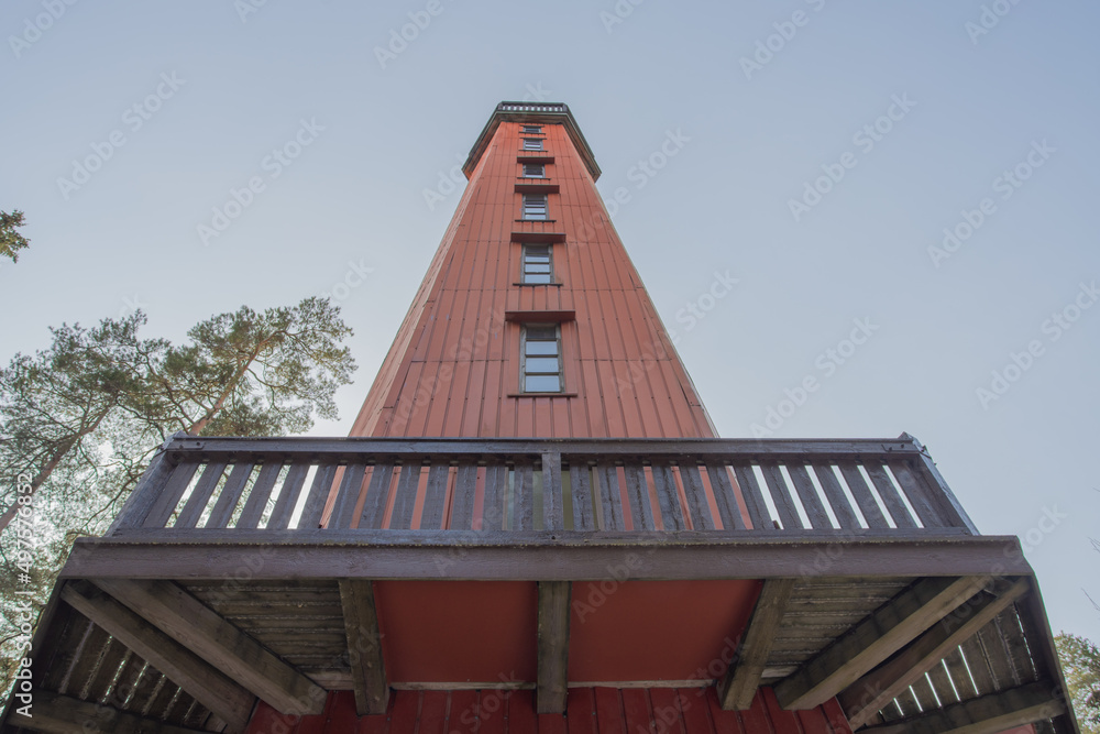 High wooden observation tower with an observation deck against the blue sky, view from the ground, Finland. The concept of nature exploration, observation deck,
