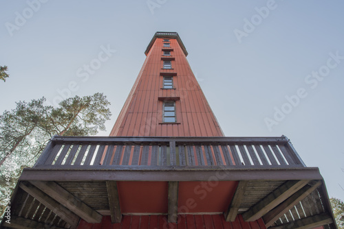 Photo High wooden observation tower with an observation deck against the blue sky, view from the ground, Finland