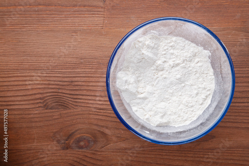 Confectionery flour in a bowl on a wooden table.