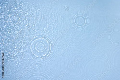 Transparent blue clear water surface texture with ripples, splashes and bubbles. Abstract nature background Water waves in sunlight. Cosmetic moisturizer micellar toner emulsion. Top view, copy space