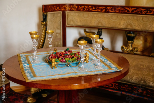 Lazne Kynzvart, Bohemia, Czech Republic, 7 August 2021: Metternich representative chateau or castle interior, baroque and classic furniture, crystal goblets with gilding and grapes in plates photo