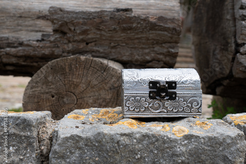 Closeup of a silver wooden jeweler box on a rough stone next to forest wooden ices in the forest photo