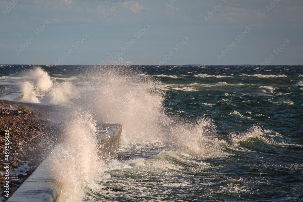 Piękne morze Bałtyckie, duże fale rozbijające się o brzeg skał, falochrony i mola. Spacer brzegiem plaży latające mewy, statki pasazerskie.