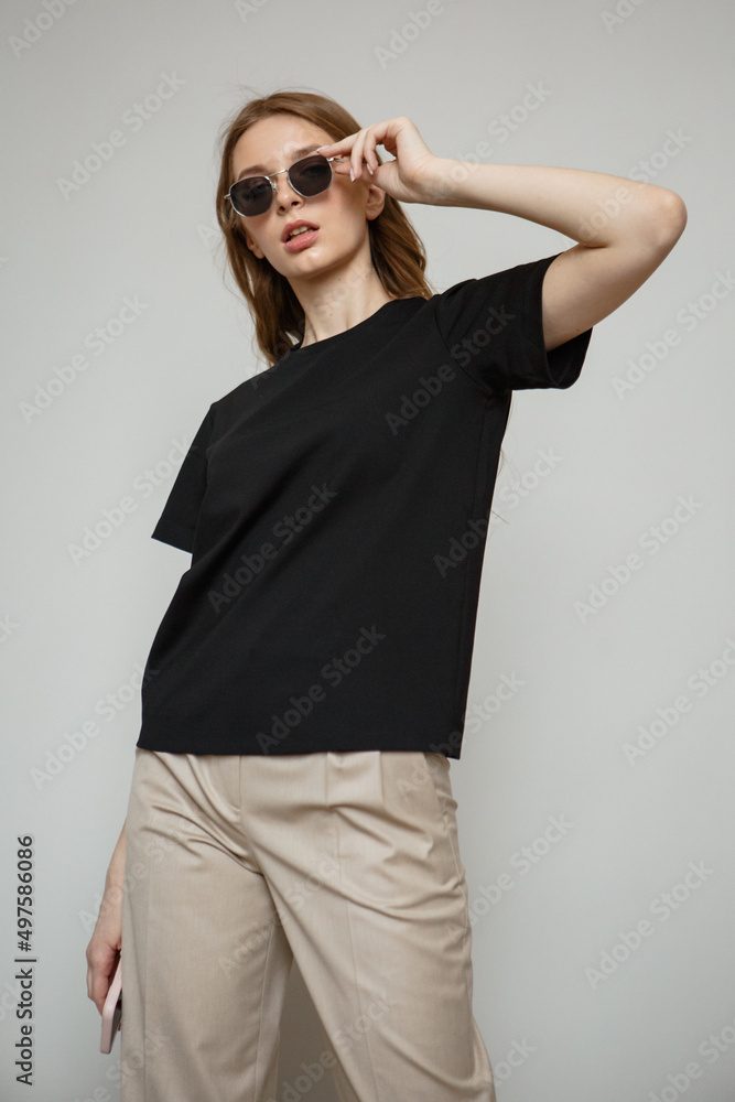A girl in fashionable clothes and black glasses stands on a studio background. Shooting clothes A girl in fashionable clothes and black glasses stands on a studio background. Shooting clothes
