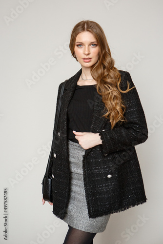 A model in black formal clothes with a black shoulder bag. Fashion show