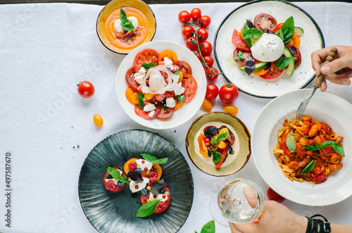 Variety of dishes on the table.  Tomato menu in the restaurant, tomato soup, mix of tomatoes with buffalo mozzarella and pesto, pork fillet, pasta with tomato sauce, tomato salad. 