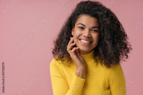 Portrait of beautiful African American woman with toothy smile, curly hairstyle looking at camera isolated on pink background. Natural beauty concept 