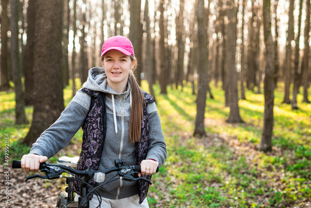 Happy young female holds steering wheel of her bike at the sunny spring forest Happy young female holds steering wheel of her bike at the sunny spring forest