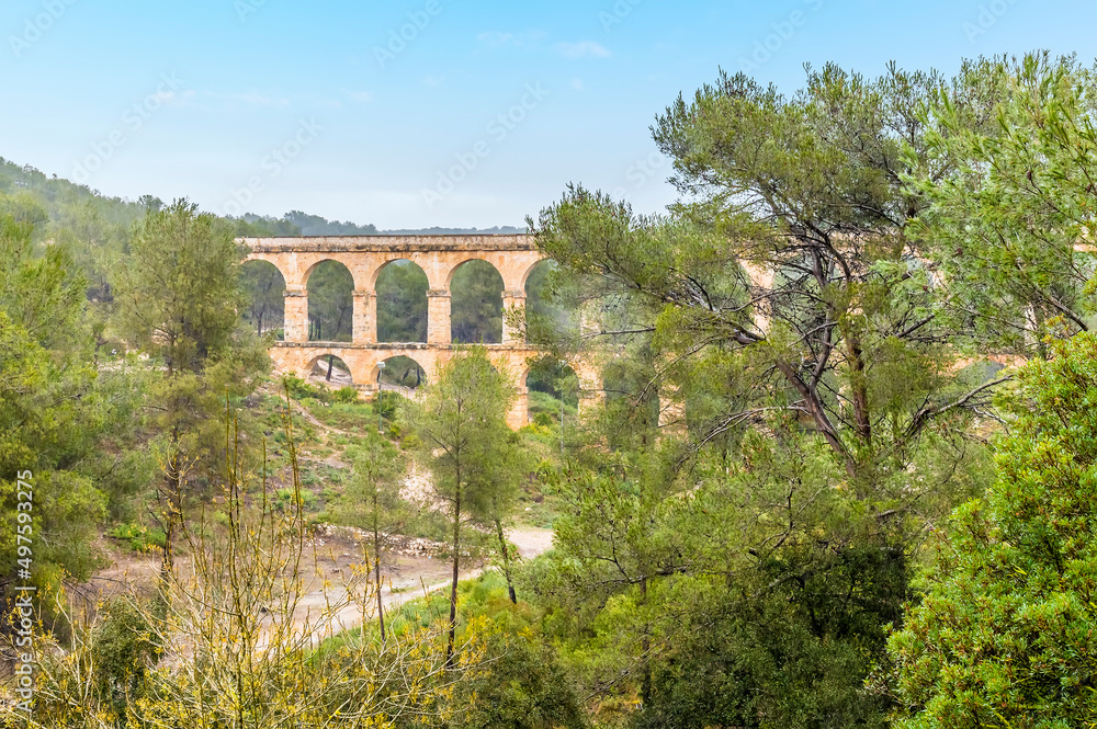 A partially obscured view towards the ancient two storey, Roman aqueduct on the outskirts of Tarragona on a spring day