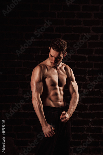 Naked torso of a young handsome man on a dark background