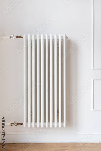 Large white heating radiator with individual adjustment hanging on wall